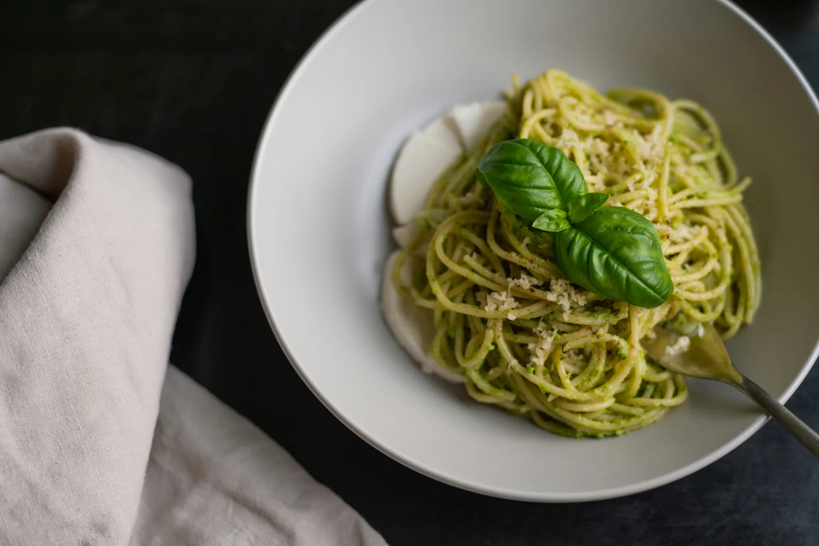 Spaghetti with pesto Genovese, fresh basil and mozzarella on a plate